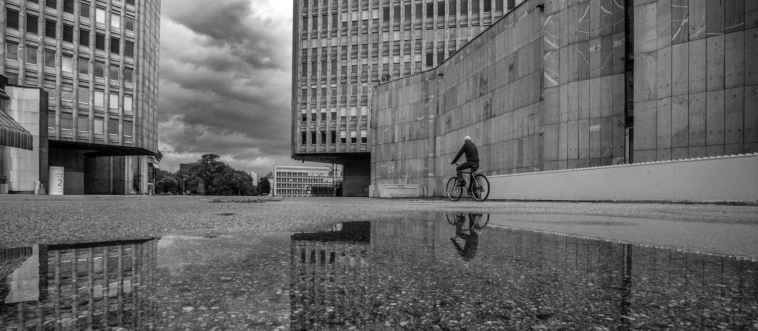 Ljubljana-Republic-square-ex-Revolution-square-ib-02-banner Man on bike and his reflection in front of buildings at the republic square, Ljubljana. Photo by Iztok Boncina.