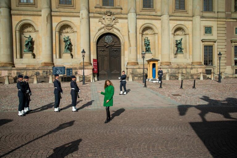 Stockholm-Sweden-Slottet-ELJ-002 A woman poses for a cellphone photo by a friend, as the Changing of the Guards, take place at Slottet, The Royal Palace, in Stockholm, Sweden, as seen from the heights of Södermalm. Photo by Eva-Lotta Jansson